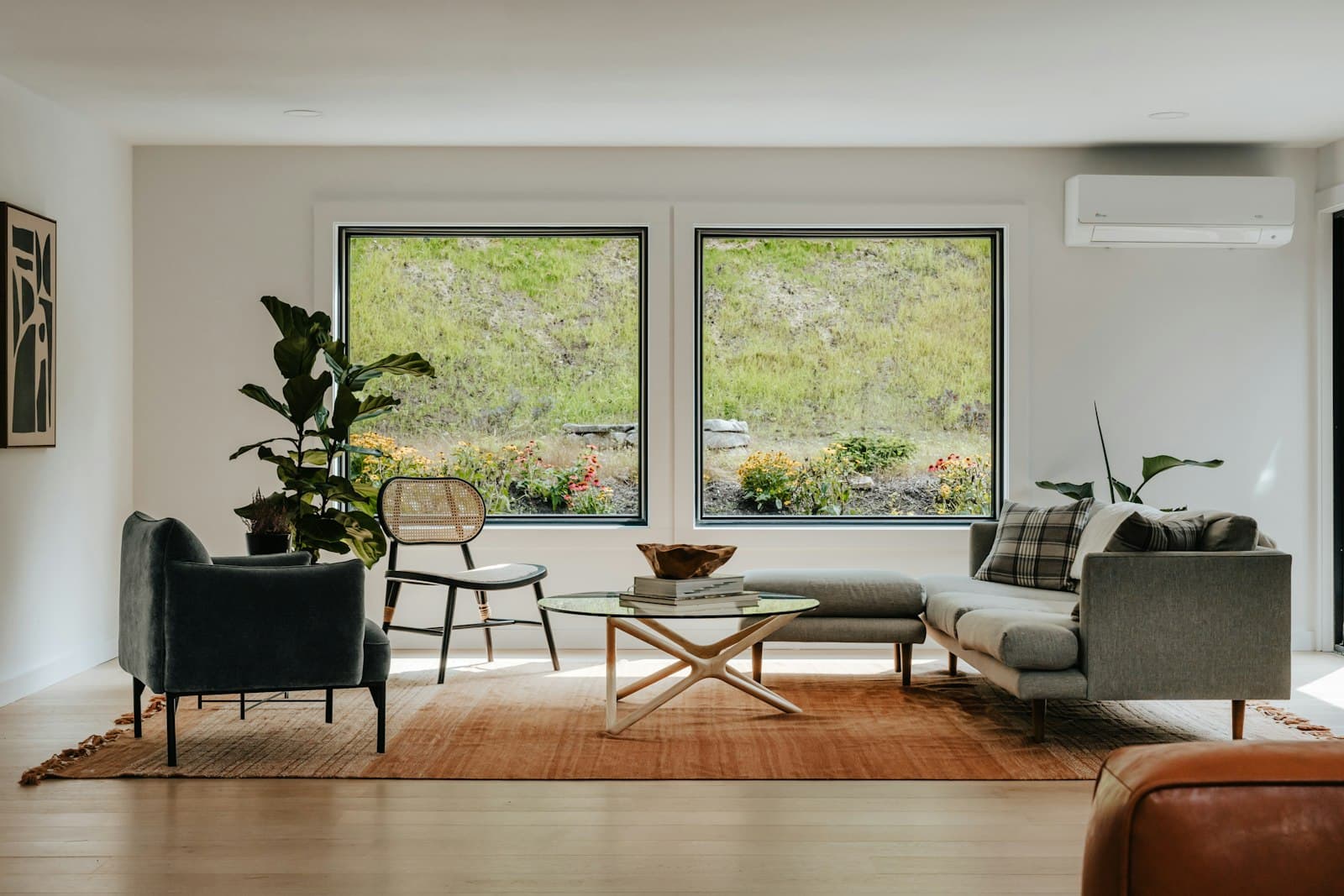 A sunlit living room with large windows opening onto a garden, natural light filling the space.